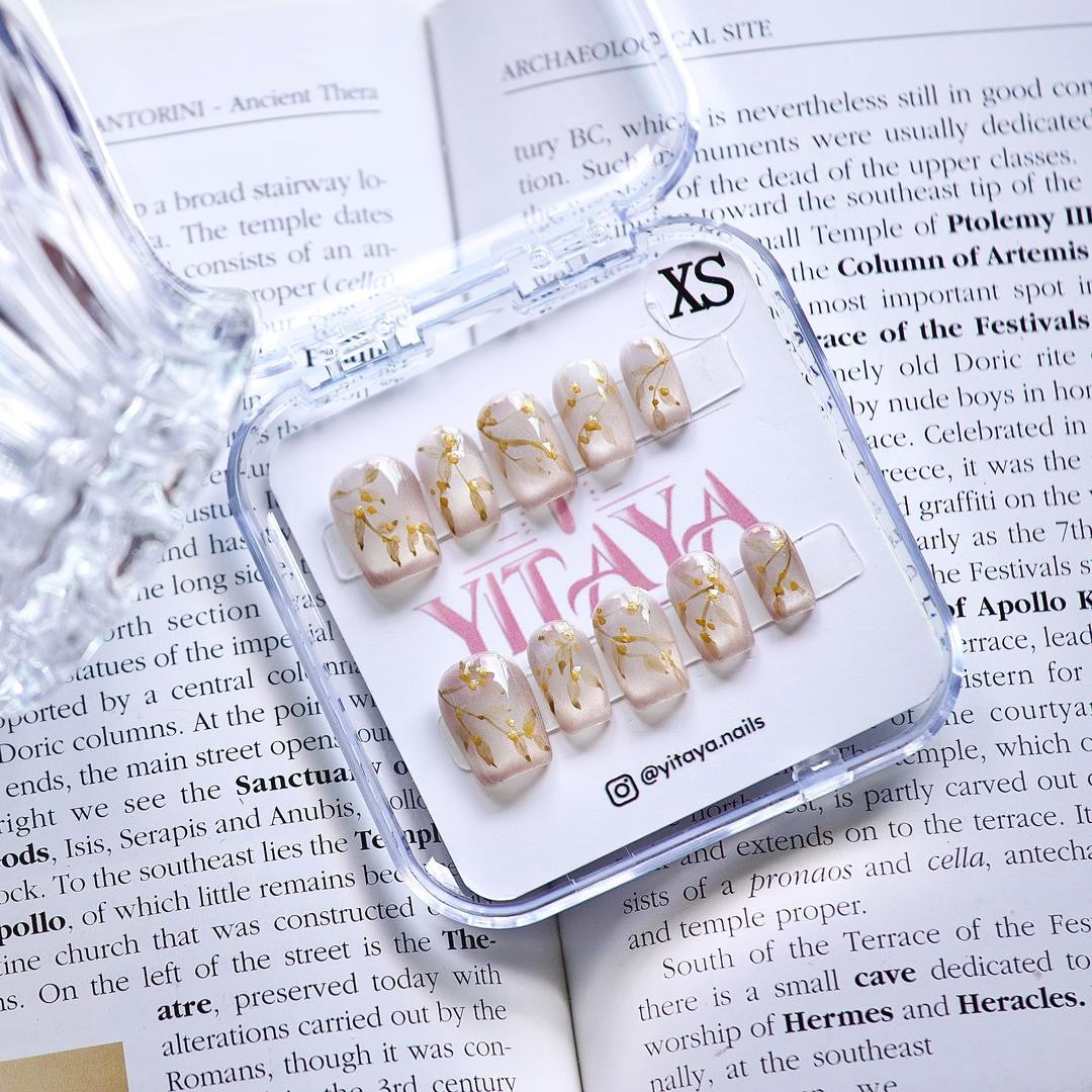 Golden Blossom press on nails, featuring soft pearly white tones adorned with intricate golden floral designs