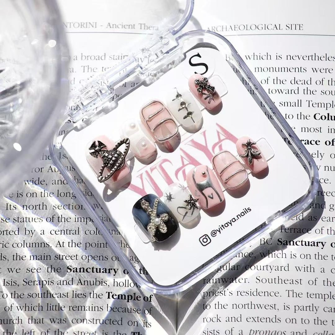 Galactic Glam Cosmic Chic Press On Nails, featuring a dreamy palette of pink, black, and white, embellished with intricate metallic charms and punk designs