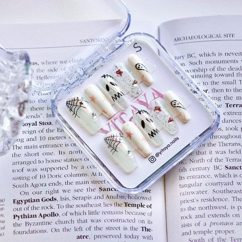 Spooky Stardust Glow press-on nails, featuring a playful mix of ghostly faces, shimmering spider webs, and pastel stars