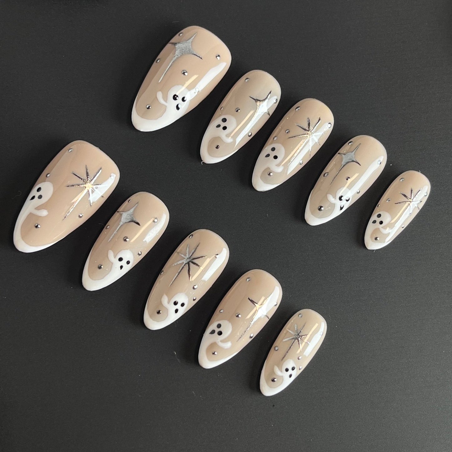 Star-Crossed Spirits Press On Nails, featuring cute ghostly figures and dazzling star-cross designs on a creamy nude base