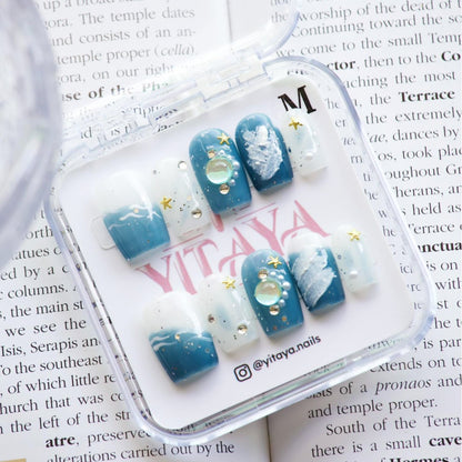 Oceanic Glow Press On Nails, featuring deep blue ocean hues, whimsical white waves, and sparkling sea-inspired accents