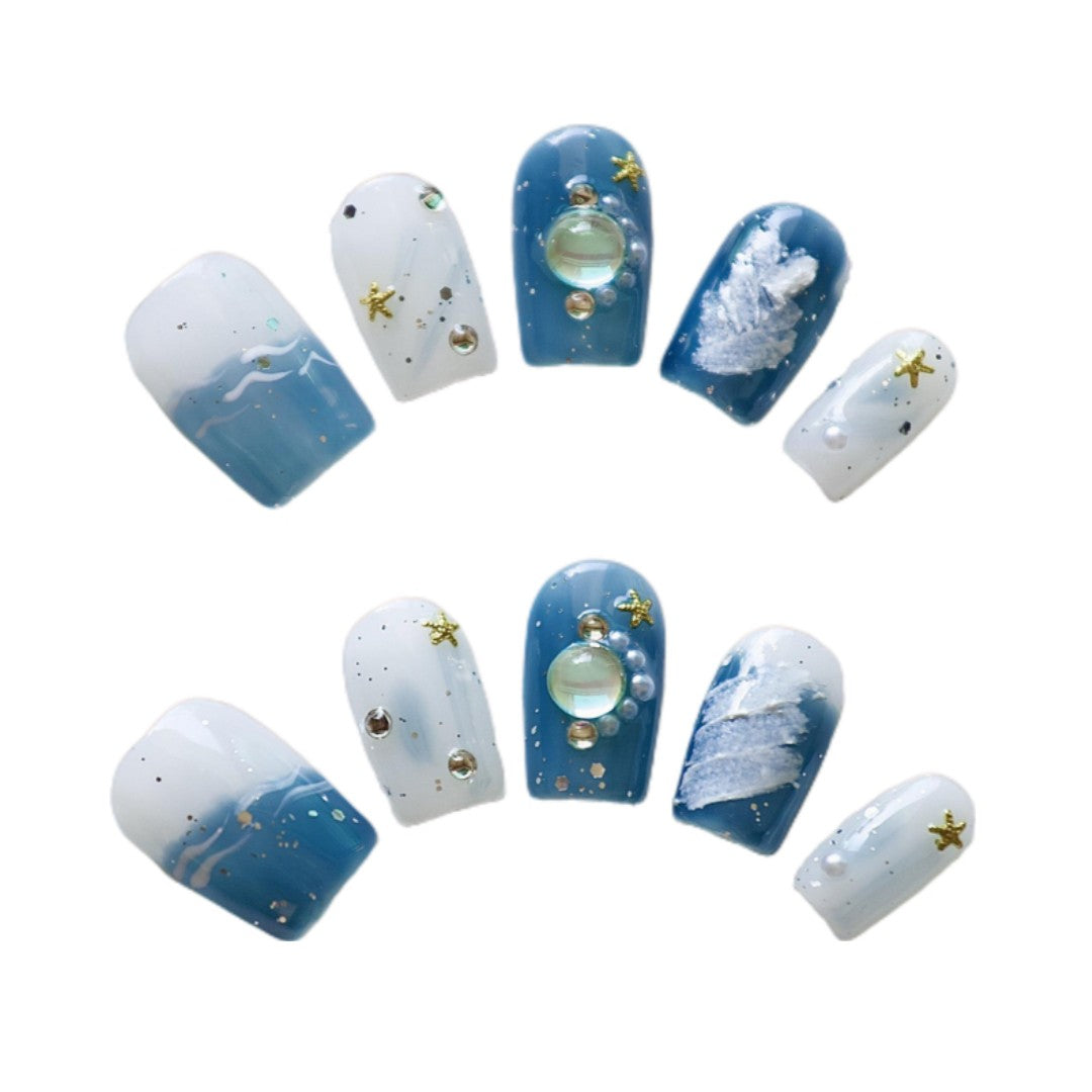 Oceanic Glow Press On Nails, featuring deep blue ocean hues, whimsical white waves, and sparkling sea-inspired accents