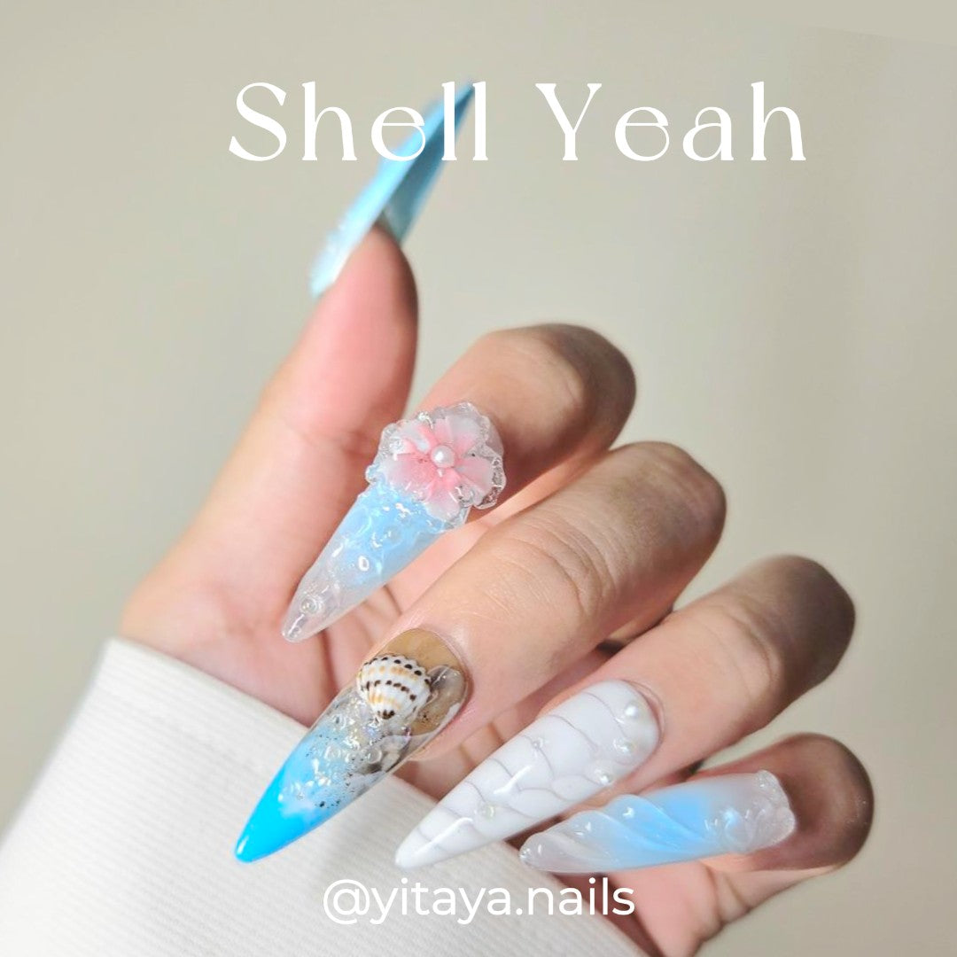 Handmade celestial press on nails featuring soft blues, whites, crescent shell, starfish, snails, and pearls.