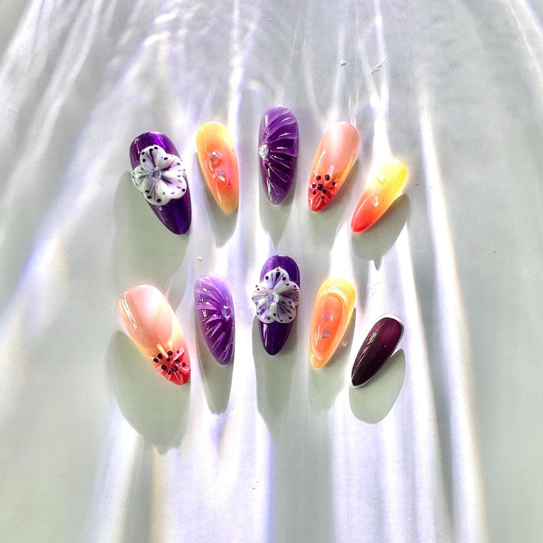 Twilight Bloom Gel Nails, blending purples, oranges, and nudes with floral accents and rhinestone